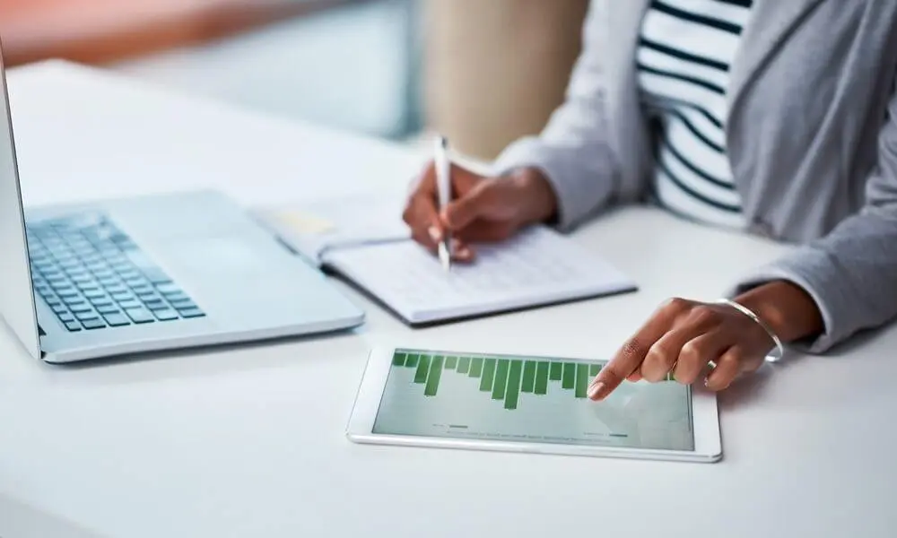 Women working with laptop while pointing to chart on tablet