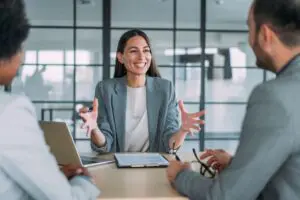 Women smiling and gesturing to two people sitting across from her in an office