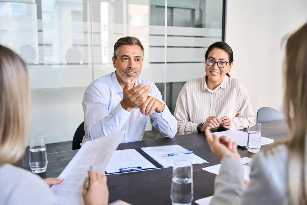 Man and women at a table talking with two people across the table in an office