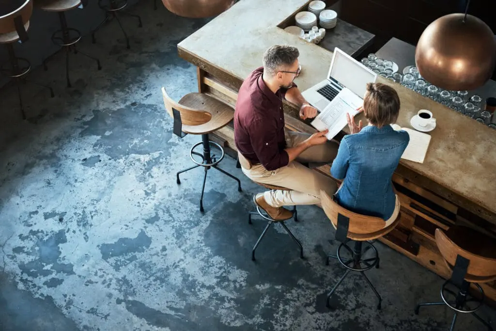 Man and woman looking at documents while sitting at the bar of a industrial looking restaurant