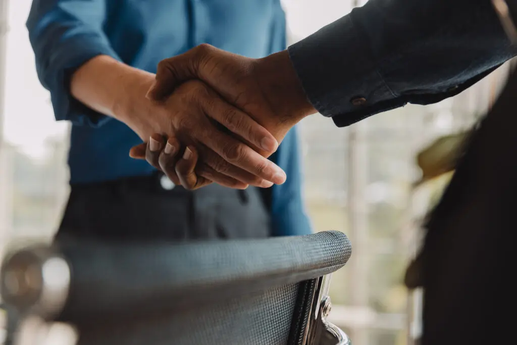 Close up photo of a man and women shaking hands in a business office