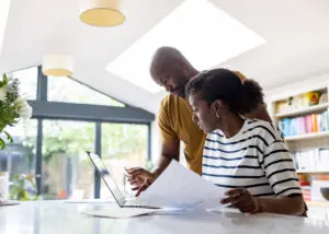 Couple looking at a credit card and financial papers while looking at a laptop