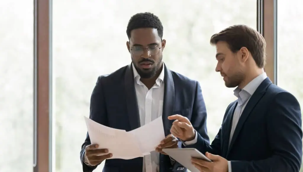 Serious caucasian businessman consulting african colleague about contract details