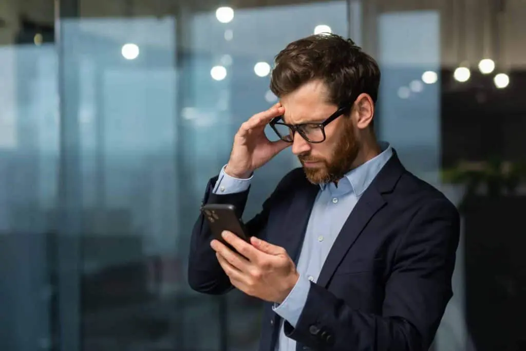 A worried man businessman holds the phone in his hands, looks. Reading bad news, received a message