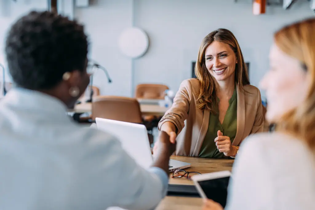 Business people shaking hands in the office. Group of business persons in business meeting. Three entrepreneurs on meeting in board room. Corporate business team on meeting in modern office. Female manager discussing new project with her colleagues. Company owner on a meeting with two of her employees in her office.