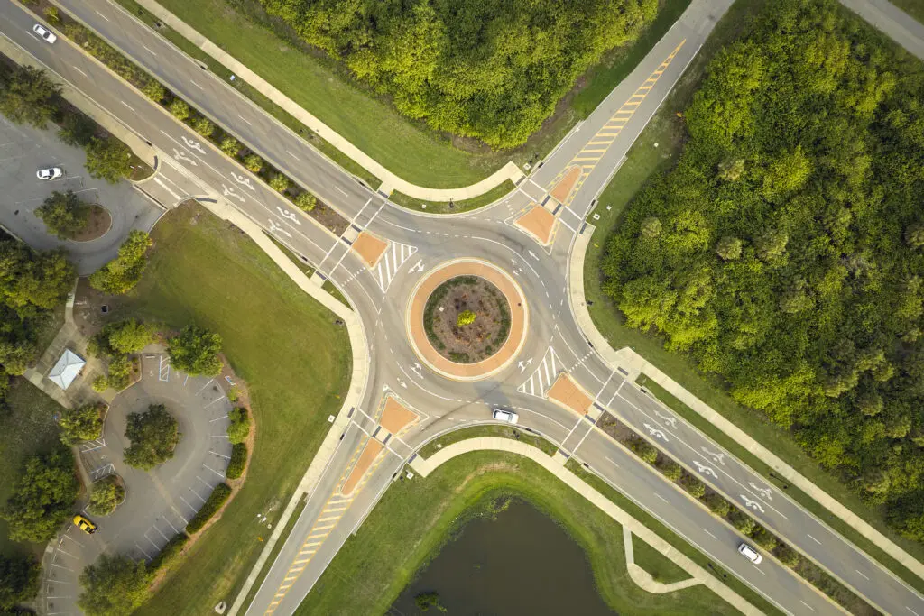 Aerial view of road roundabout intersection with moving cars traffic. Rural circular transportation crossroads.