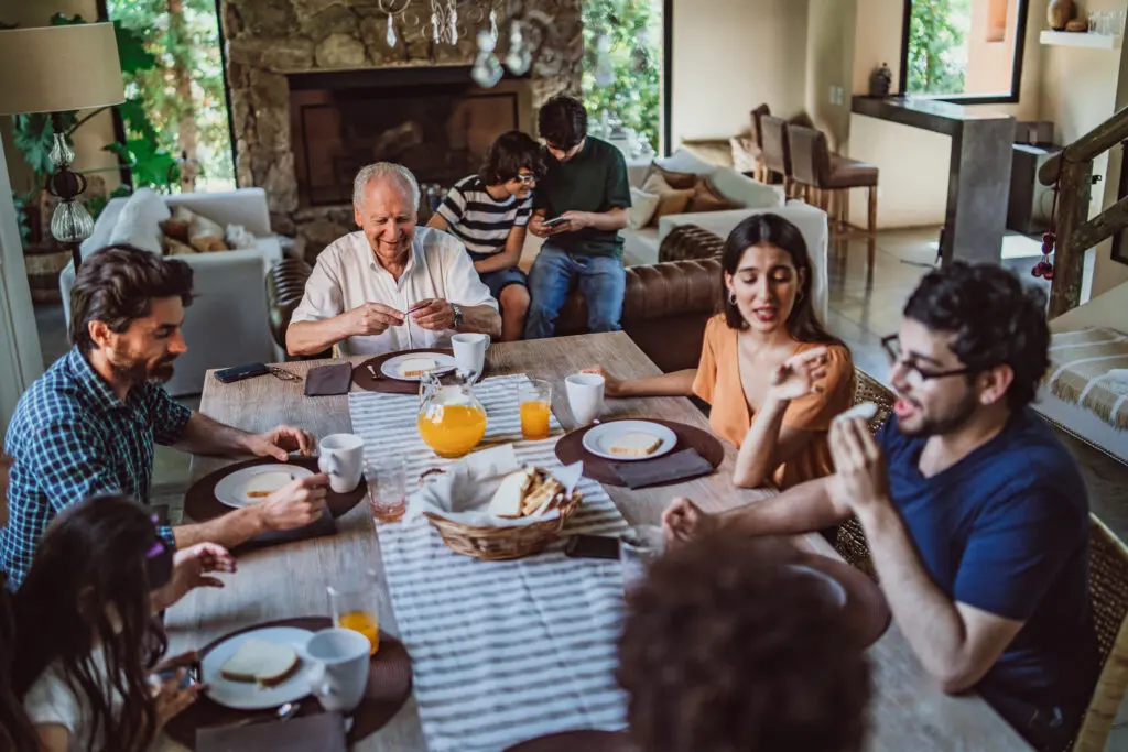 Big family sitting at dinner table and having breakfast together.