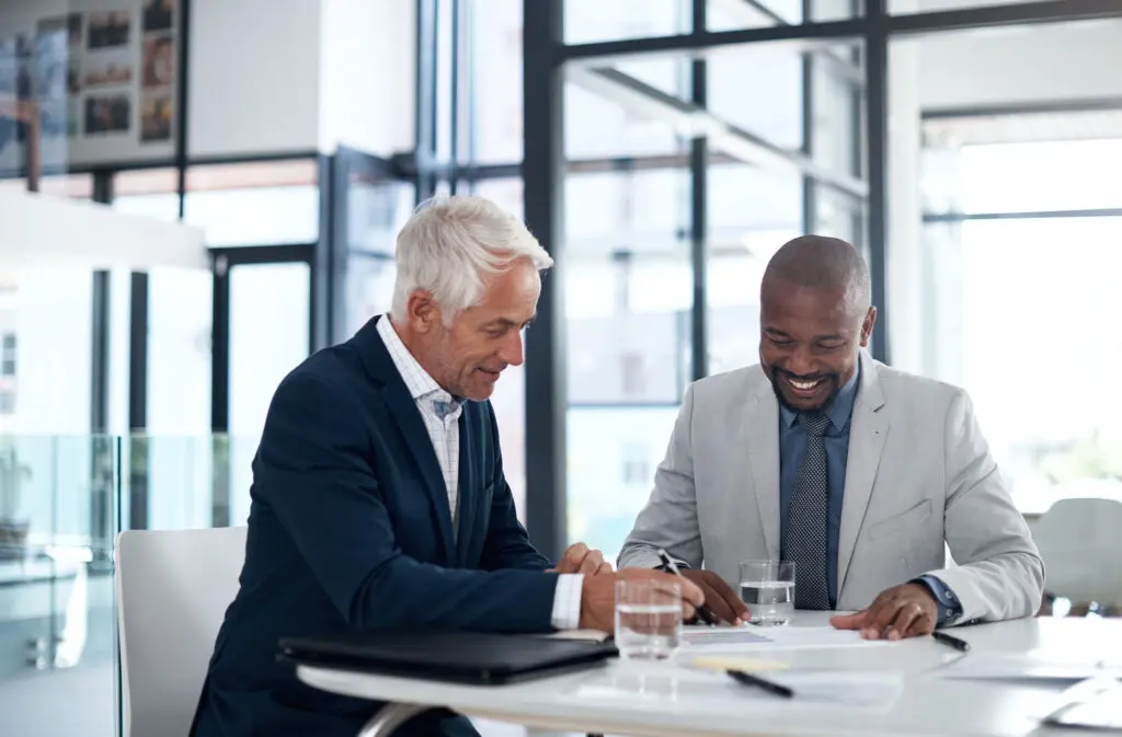 Shot of two businessmen going through paperwork together in an office. Insured Cash Sweep page.