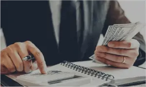 Financial advisor counting cash using notebook