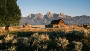 Grand Teton mountains in Wyoming with a abandon log cabin in the foreground