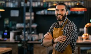 Man standing in restaurant with arms cross smiling at camera