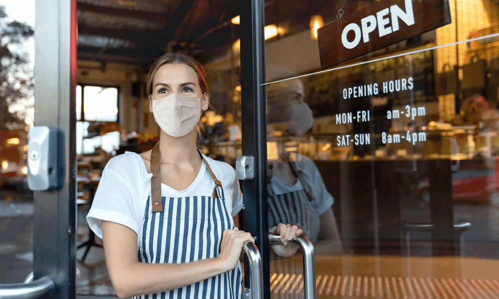 Business owner standing in door looking in distance with mask on