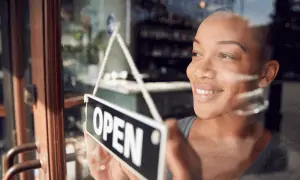 Woman looking out window with business sign 