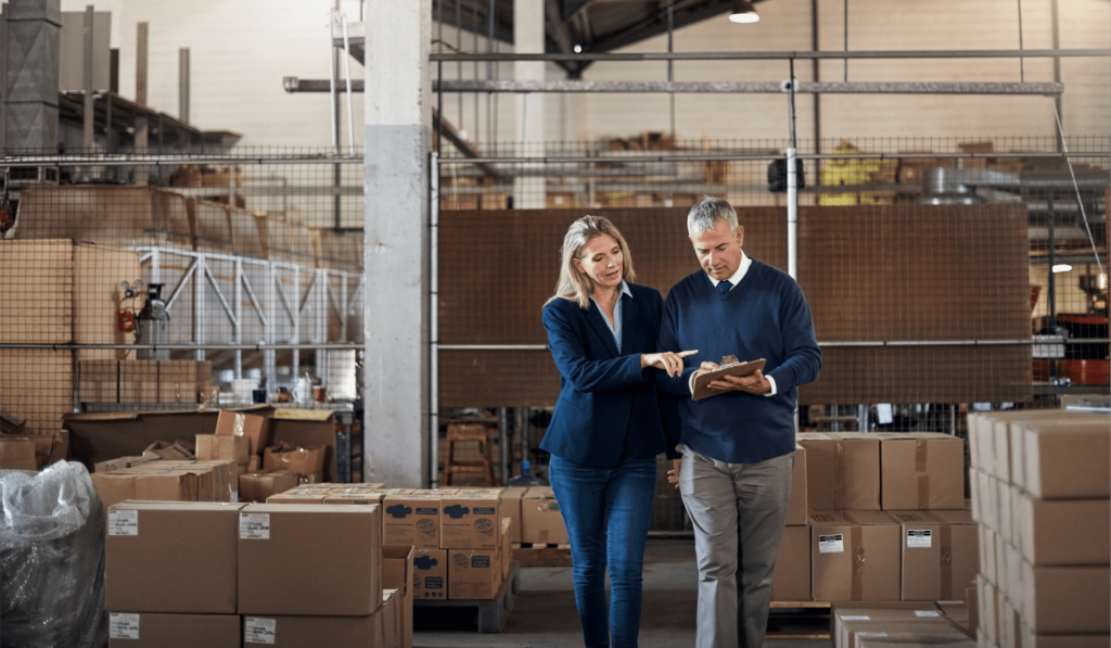 Two people walking in a warehouse and looking at a tablet
