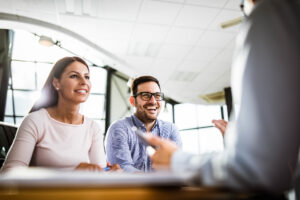 Young happy couple communicating with their financial advisor on a meeting in the office.