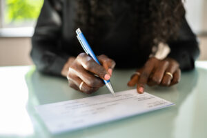 African Woman Writing Check - Check Fraud Blog Article