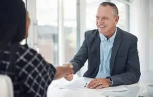 Shot of a mature businessman shaking hands with a colleague in a modern office. Consider private banking article