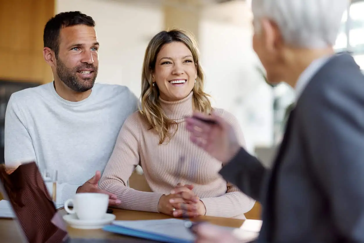Happy couple communicating with their mortgage origination representative in the office.