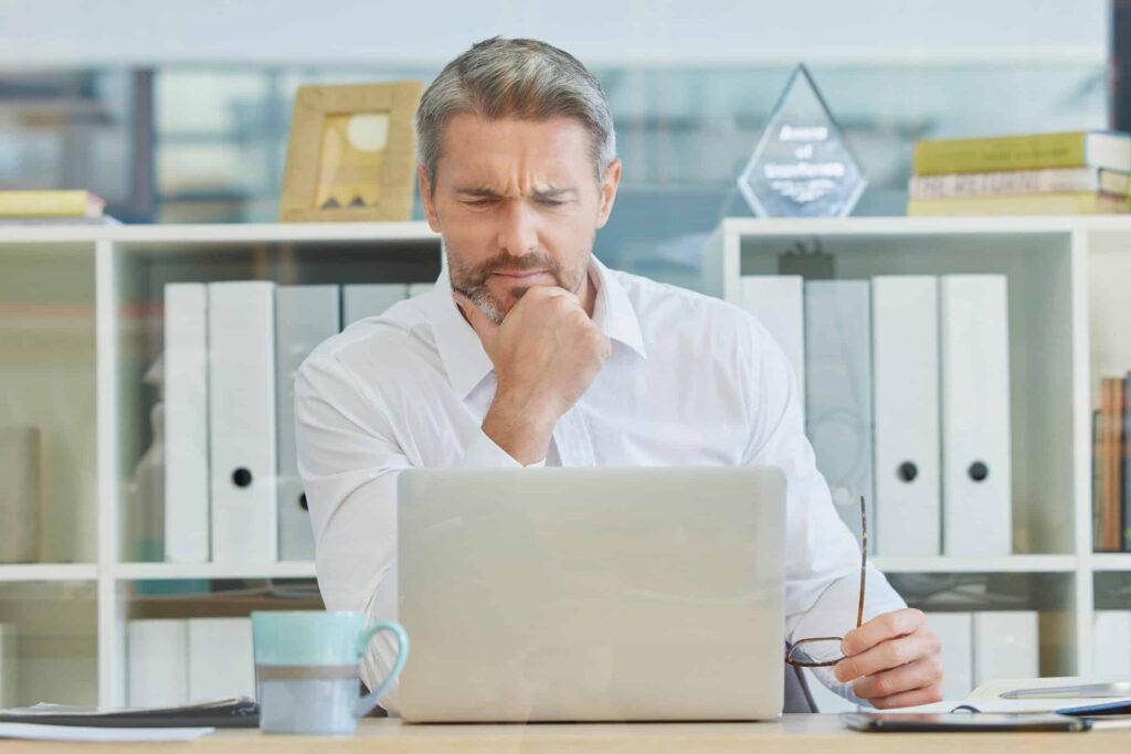 Business man in an office looking puzzled at his computer screen