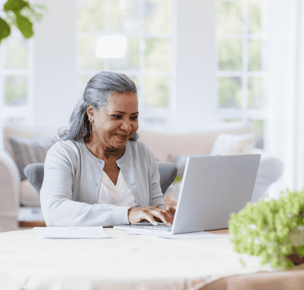 Gray haired woman looking at computer at home