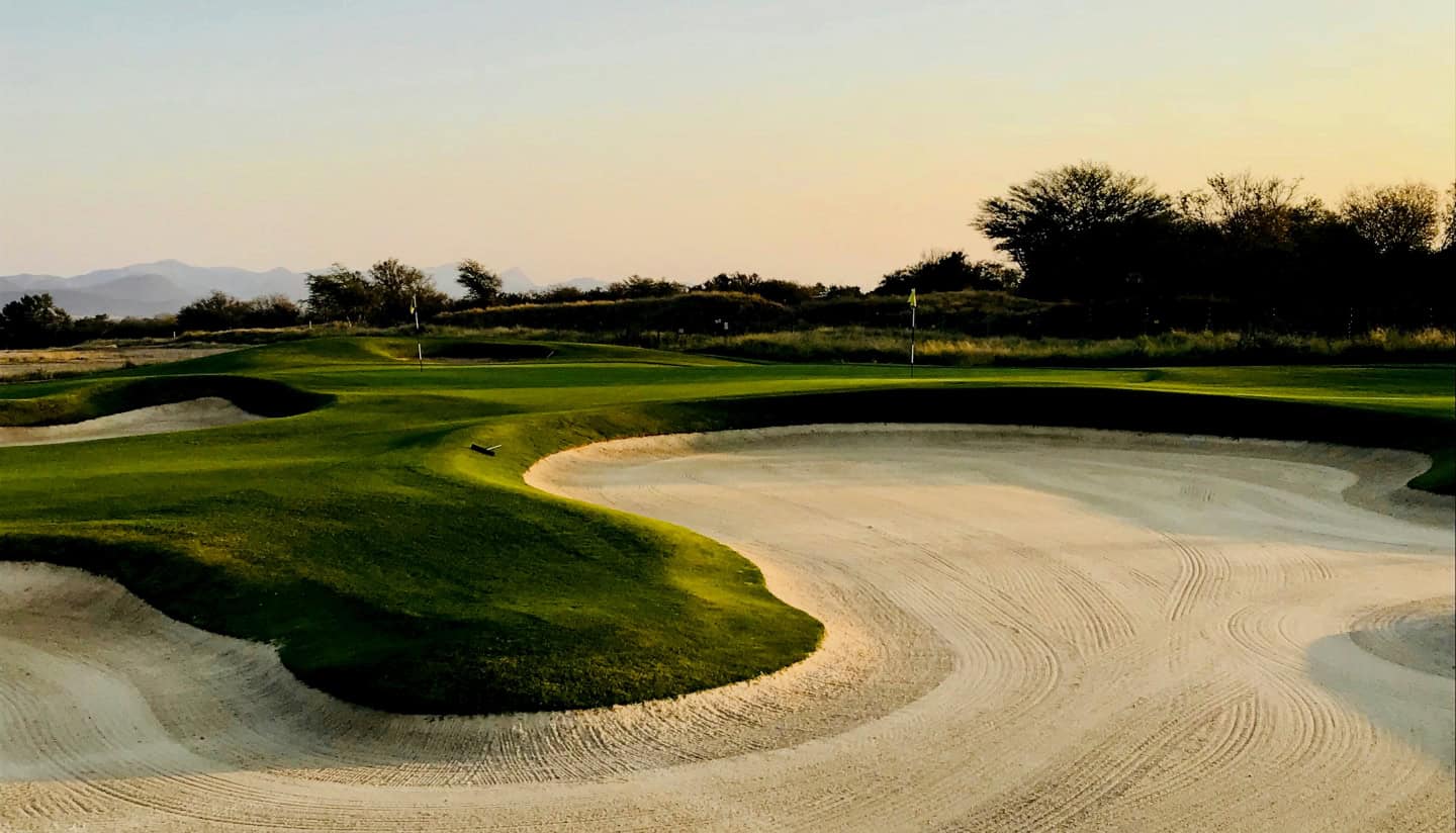 A golf course with green and 2 sandpits