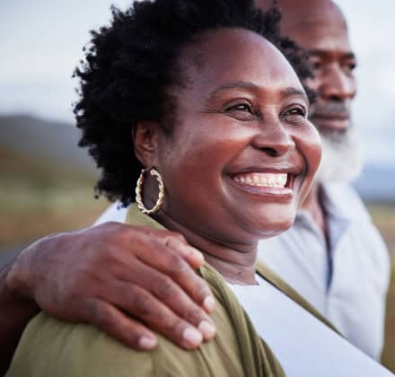 Close up of women smiling while standing with husband looking outward