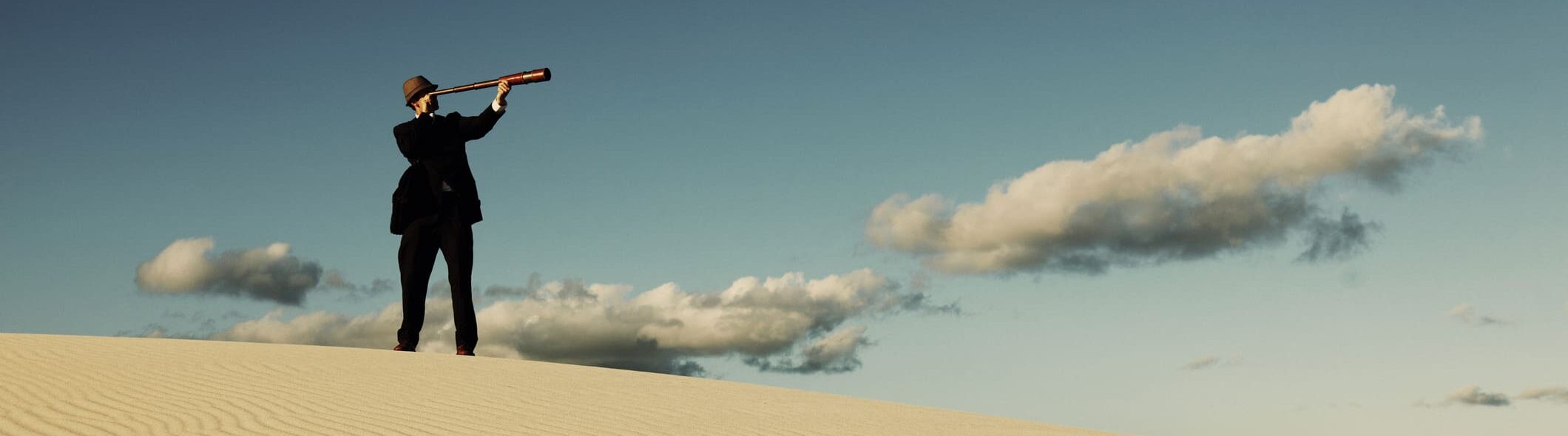 A male businessman looks for the next business opportunity while lost in the desert. Plenty of conceptual copy space for your copy.