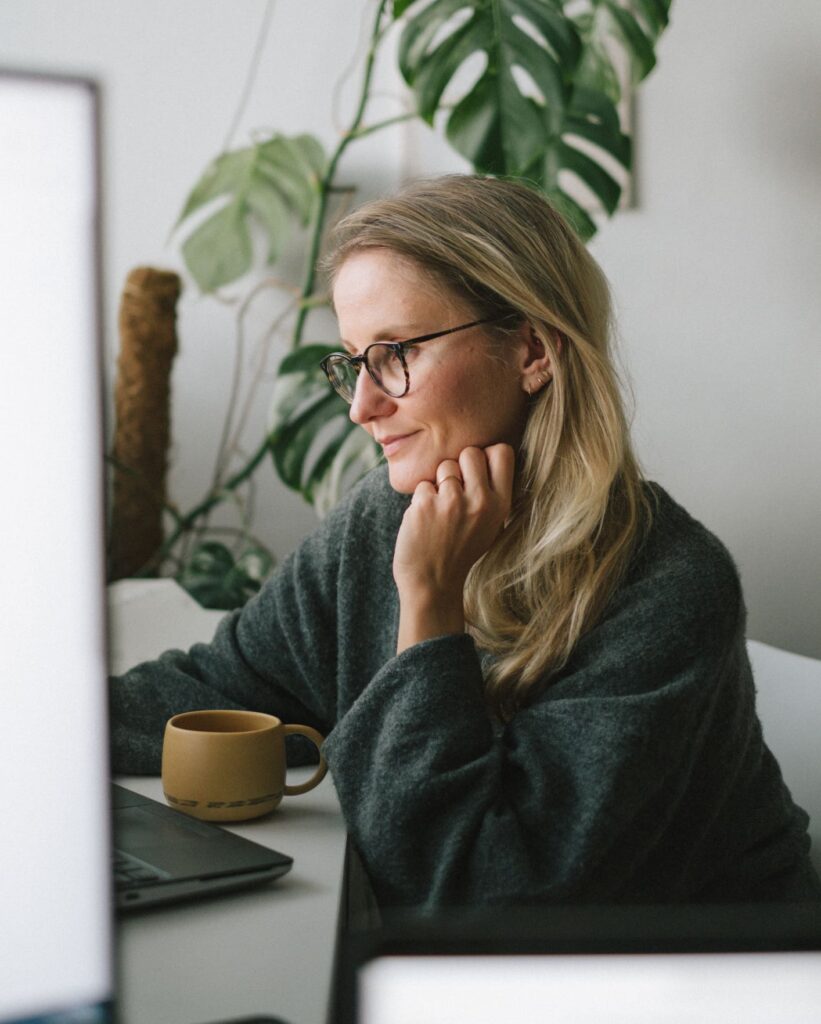 Young woman works on computer at home, hot beverage